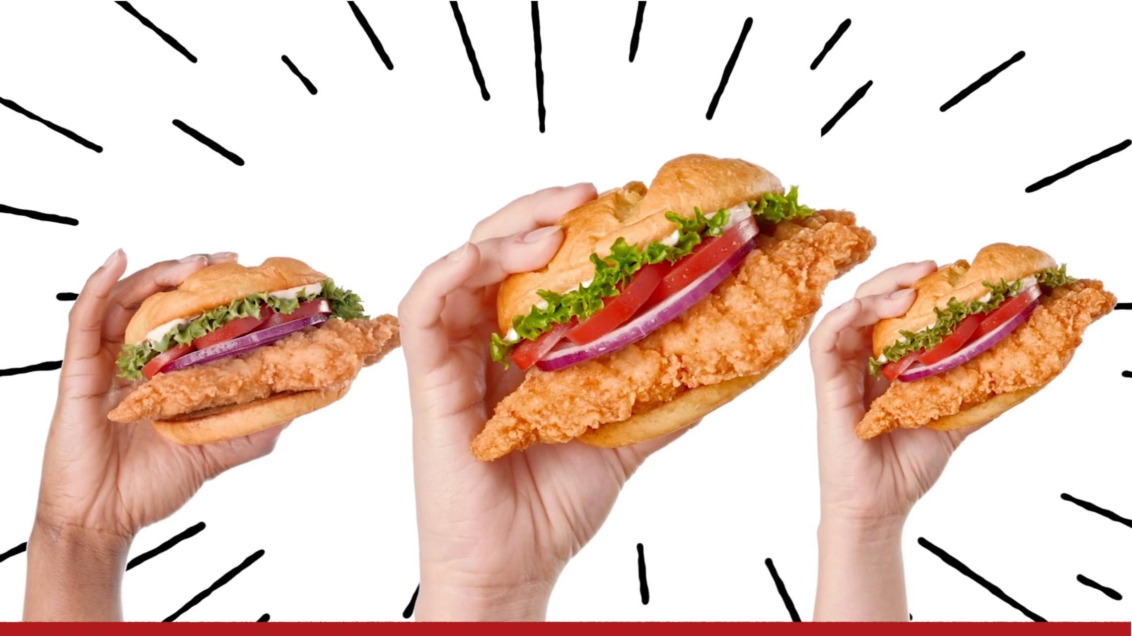 Image of three hands holding up crispy chicken sandwiches.